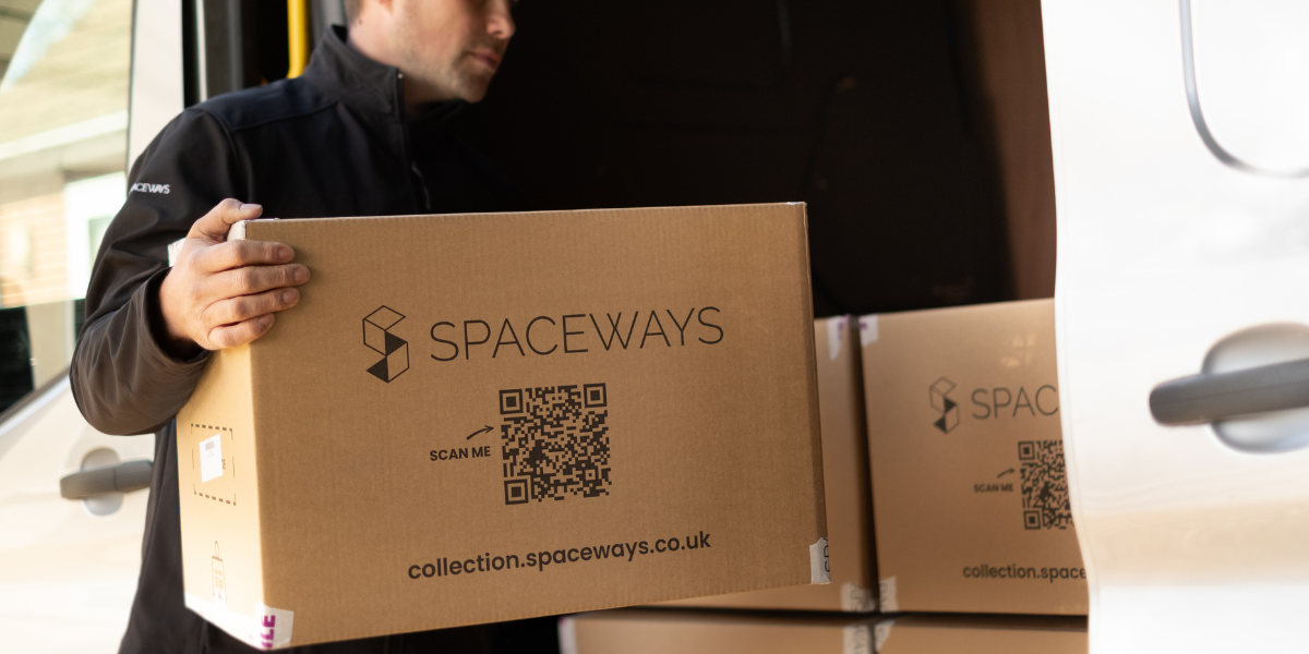 Picture of a storage worker transporting a student storage box into a van where there are other student storage boxes.