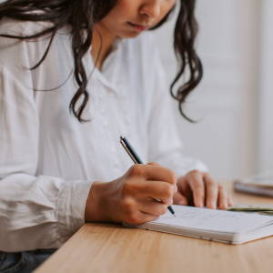 Picture of a student writing up a budget on a notepad 