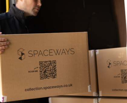 Picture of a storage worker transporting a student storage box into a van where there are other student storage boxes.